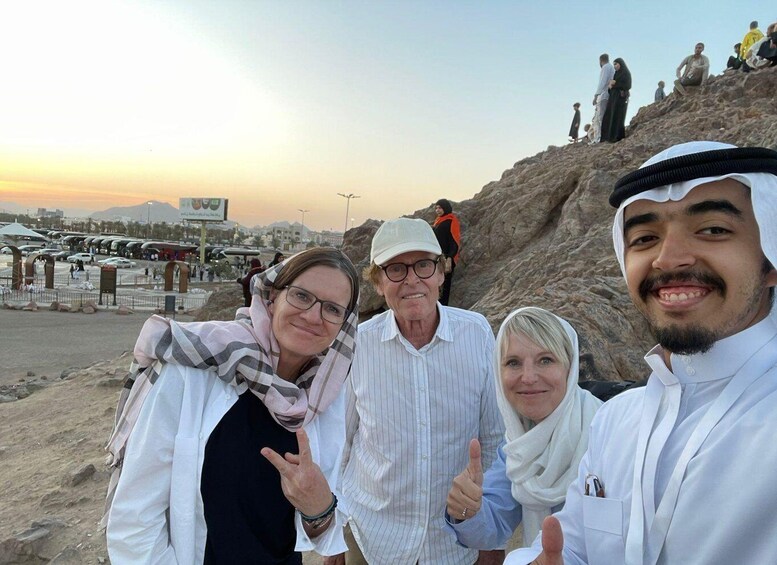 A group of people at a rocky outcrop with a sunset in the background. 5