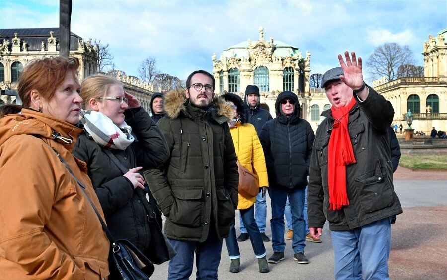 A group of people walking in front of a historic building with ornate architecture. 3