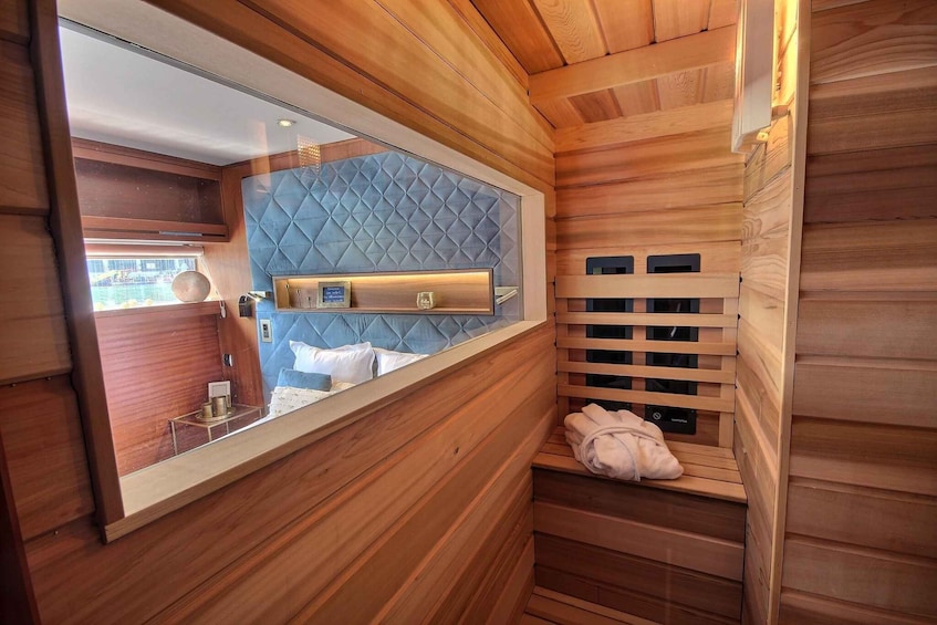 A wooden interior with a large mirror, a tufted headboard, and a sauna bench. 4