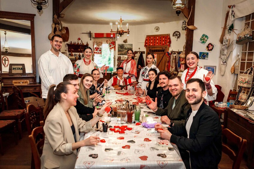 A group of people around a table with a tablecloth decorated with strawberries, in a room with wooden furniture and various decorations. 3