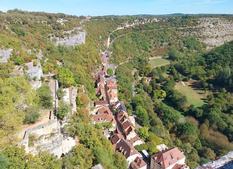 A village nestled in a valley with terraced houses, a stone wall, and a river. 5