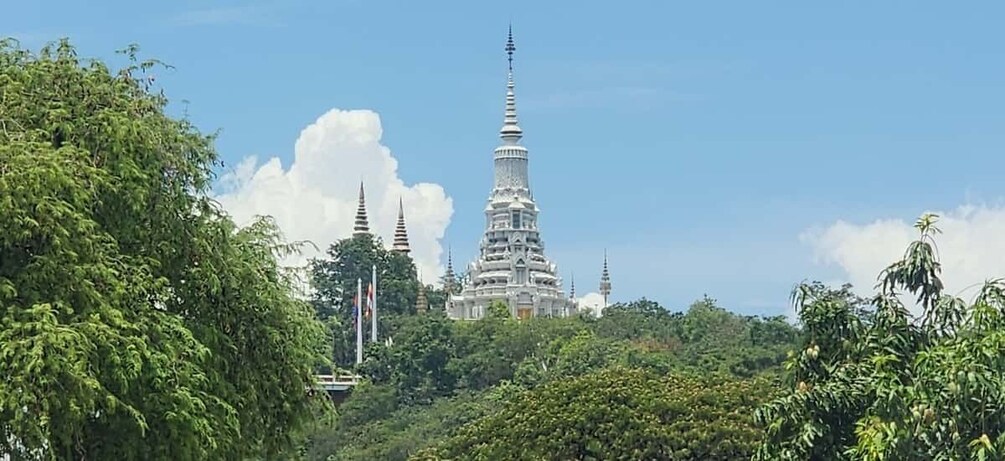 A white temple complex with multiple spires, surrounded by lush greenery. 4