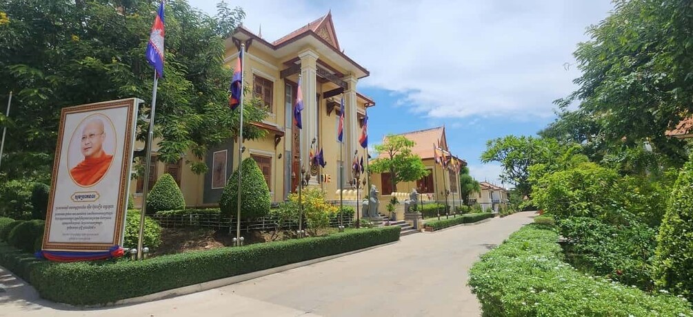 A colonial-style building with flags, a well-maintained garden, and a clear sky. 2