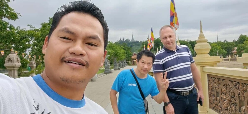 A person taking a selfie with two others in a temple setting. 1