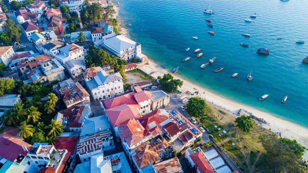 An aerial view of a coastal town with buildings, a beach, and numerous boats. 5