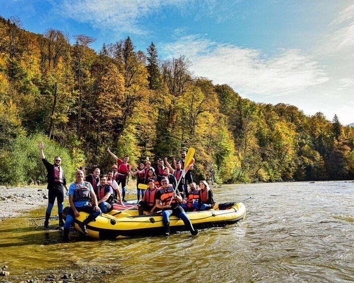 A group of people on a yellow raft in a river surrounded by autumn-colored trees. 2
