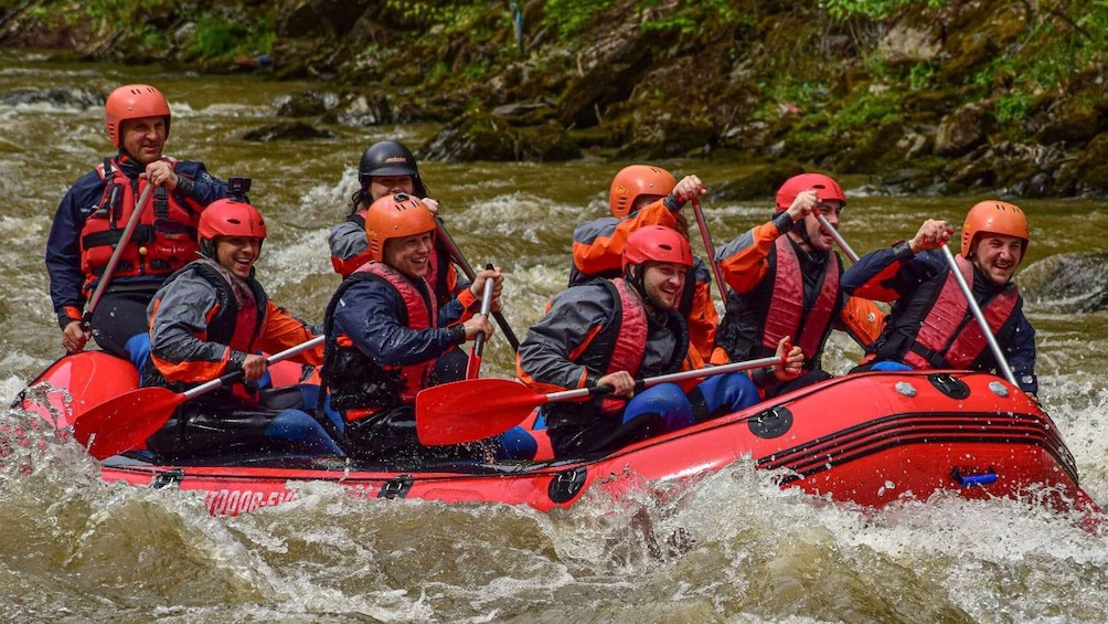 A group of people in a red raft navigating a river. 1