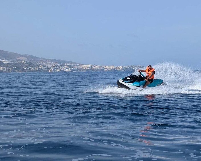 A person jet-skiing on a body of water with a coastal town in the background. 3