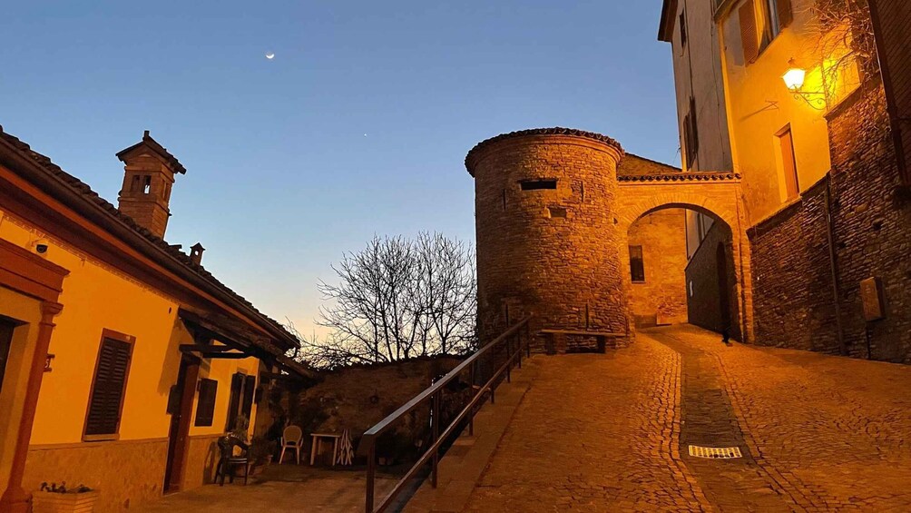 A historic stone tower, a cobblestone street, and a building with a bell tower. 4
