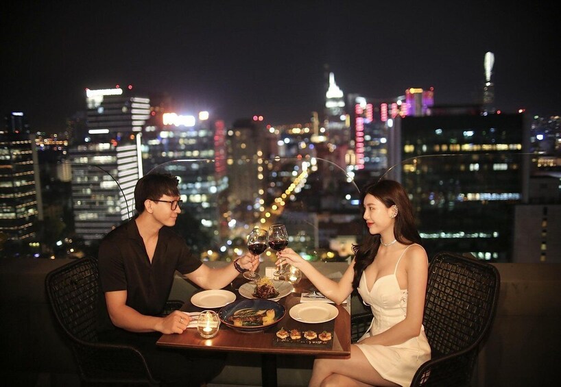 A couple dining at a table with a cityscape in the background. 1