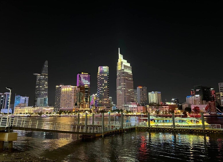 A city skyline at night with illuminated buildings and a bridge over water. 3