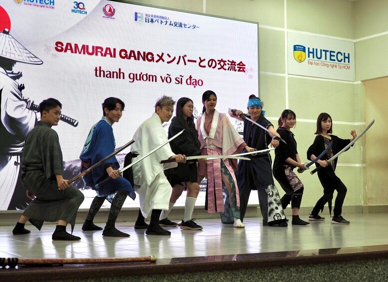 A group of people in traditional samurai attire performing a synchronized martial arts routine on a stage. 3