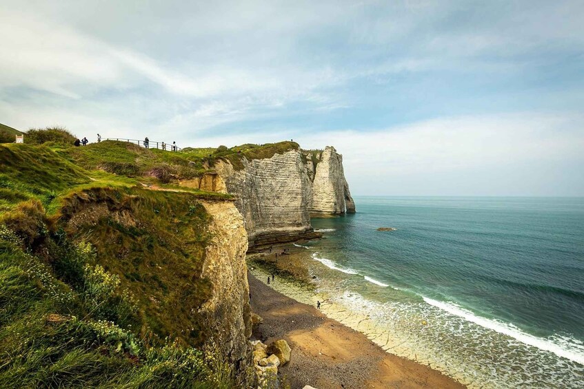 A coastal cliff with a beach, ocean, and a path for visitors. 4