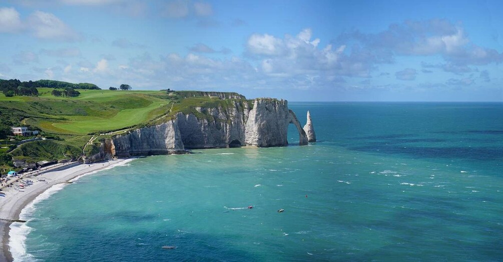 A coastal landscape with cliffs, a beach, and boats. 5