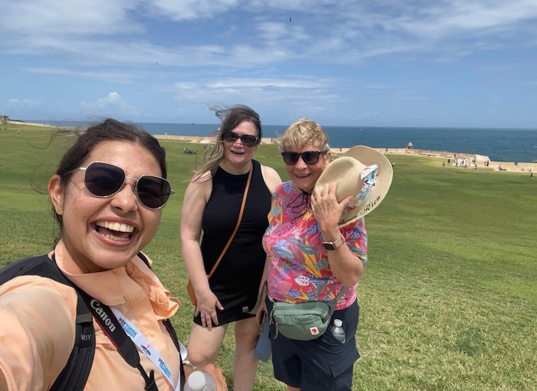 Three people on a grassy field with a body of water and a distant shoreline in the background. 1