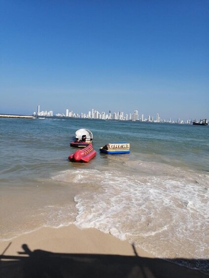 A beach with two inflatable boats and a city skyline in the background. 2