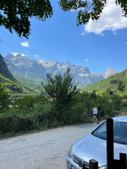 A person walking along a gravel path with a mountain range in the background. 5