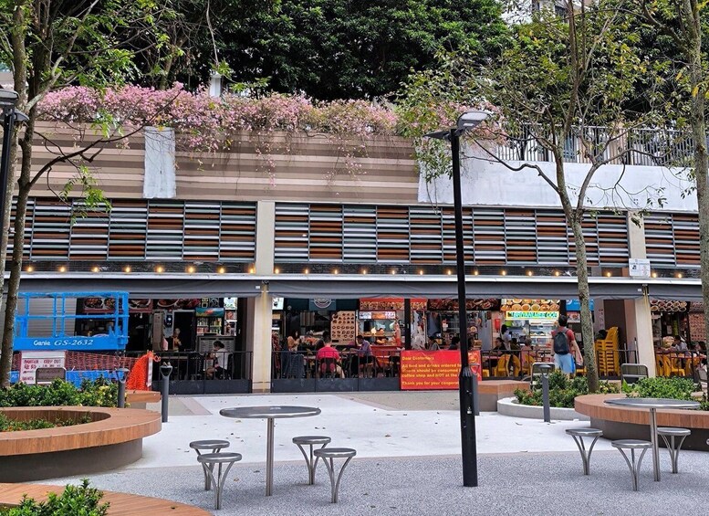 A street with outdoor seating, a blue bus, and a building with multiple shops. 4