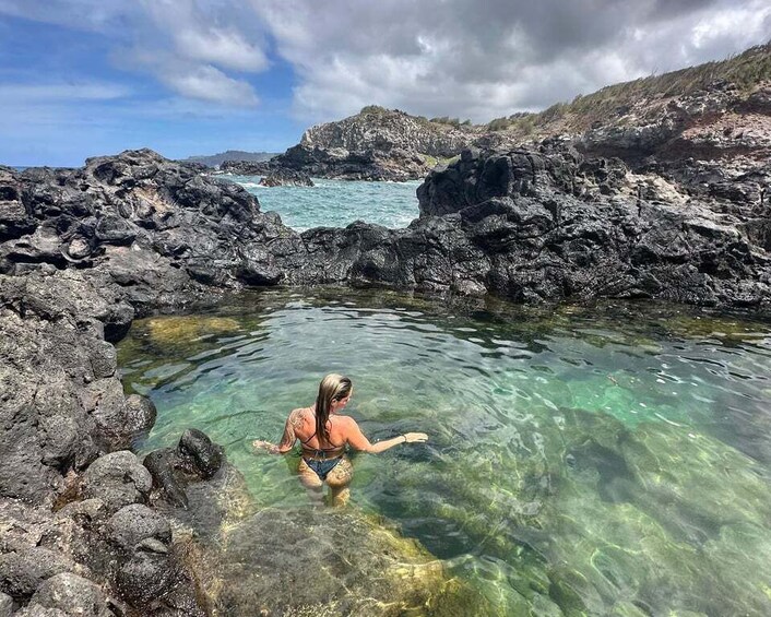 A person swimming in clear water surrounded by rocky terrain. 2