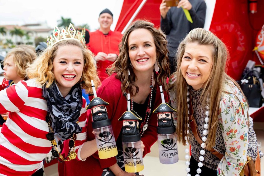 Three people wearing pirate-themed accessories and a red vehicle in the background. 4