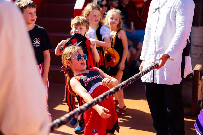 A child in a Buccaneers costume holding a baton, with spectators in the background. 2