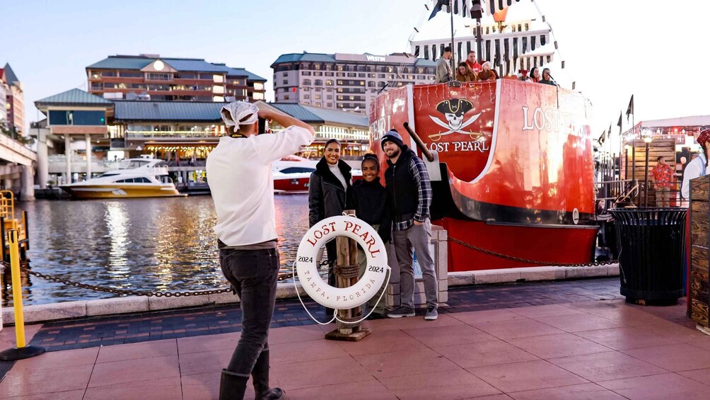 A group of people posing with a 'Lost Pearl' sign and a lifebuoy in Tampa, Florida. 5