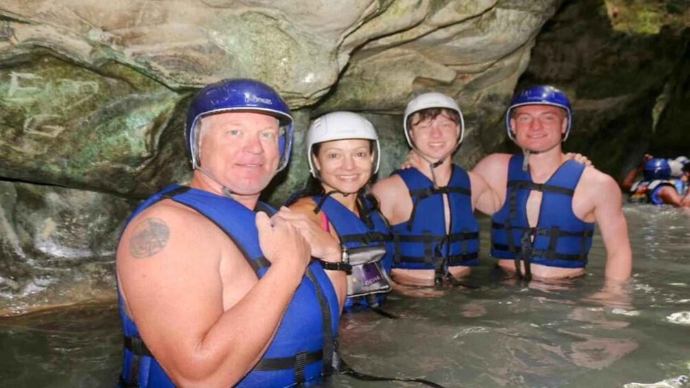 A group of people in a cave with water, wearing helmets and life vests. 3