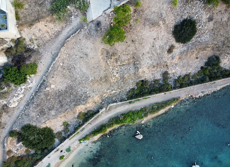 A coastal road with a clear view of the sea, rocky terrain, and sparse vegetation. 3