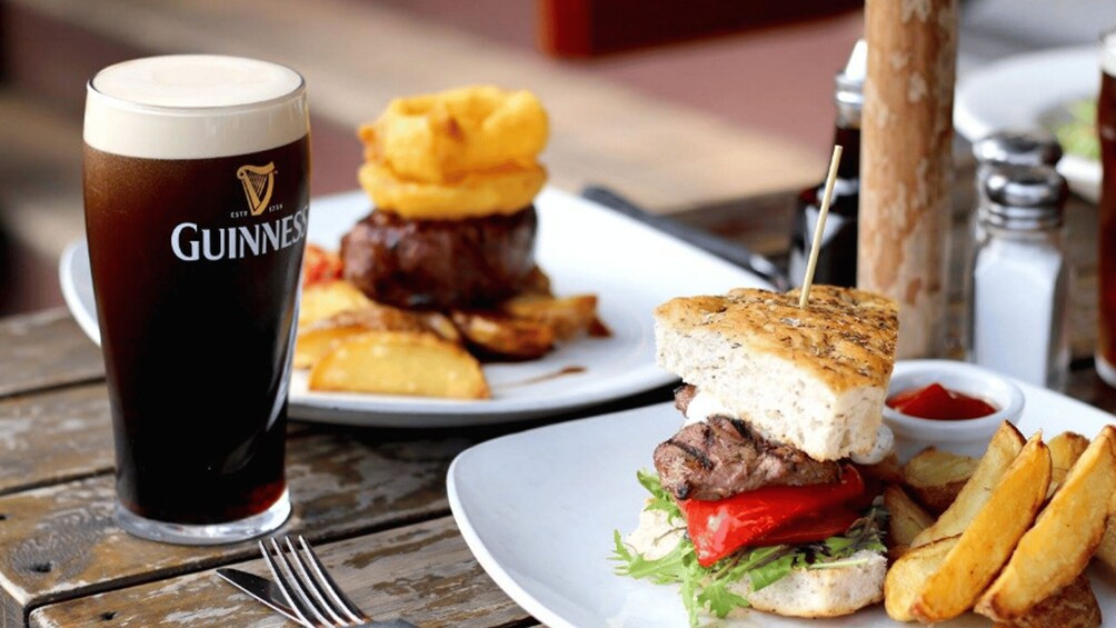 A meal with a burger, fries, and a glass of Guinness beer on a wooden table. 3