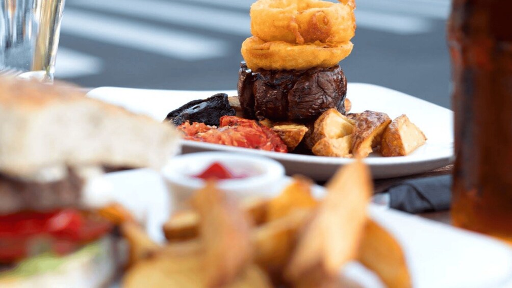 A plate of food with a steak, onion rings, and fries. 1