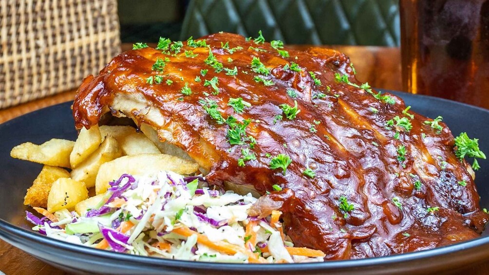 A plate of barbecued ribs with coleslaw and fries. 4