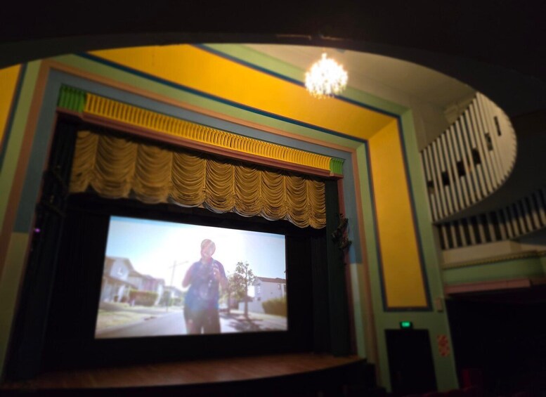 A theater with a large screen, a chandelier, and a curved ceiling. 2