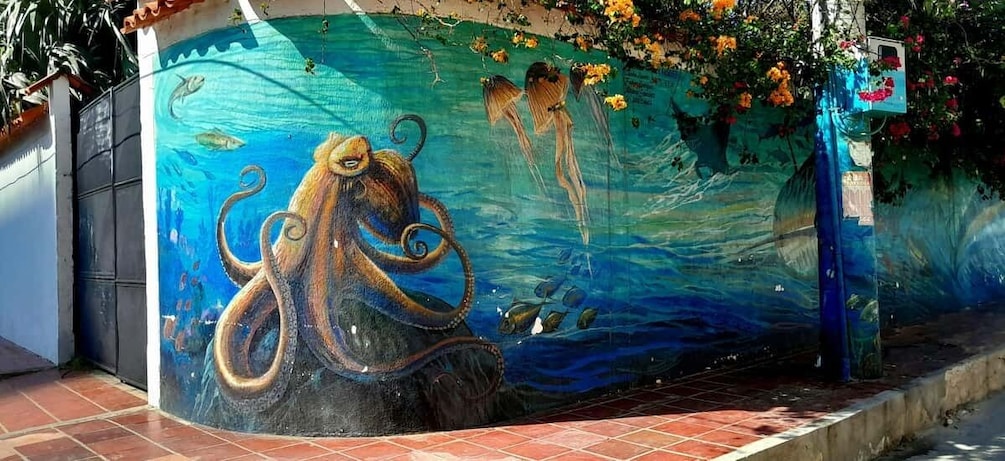 A mural of an octopus on a wall with flowers and a blue tarp. 4
