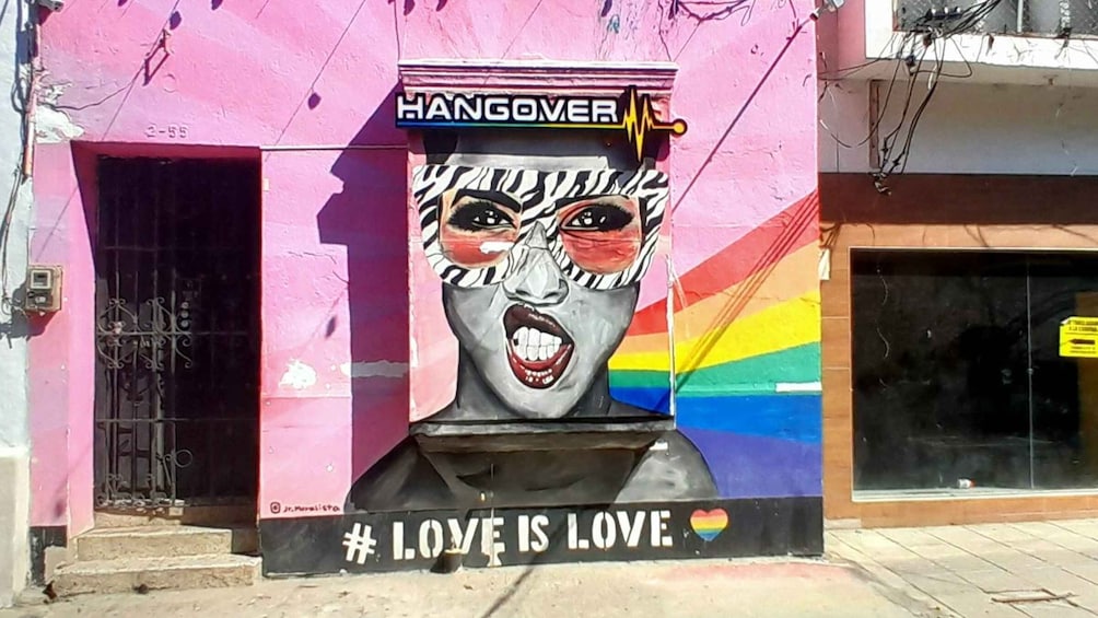 A building facade with a mural of a face, a rainbow flag, and the text '#LOVE IS LOVE.' 1