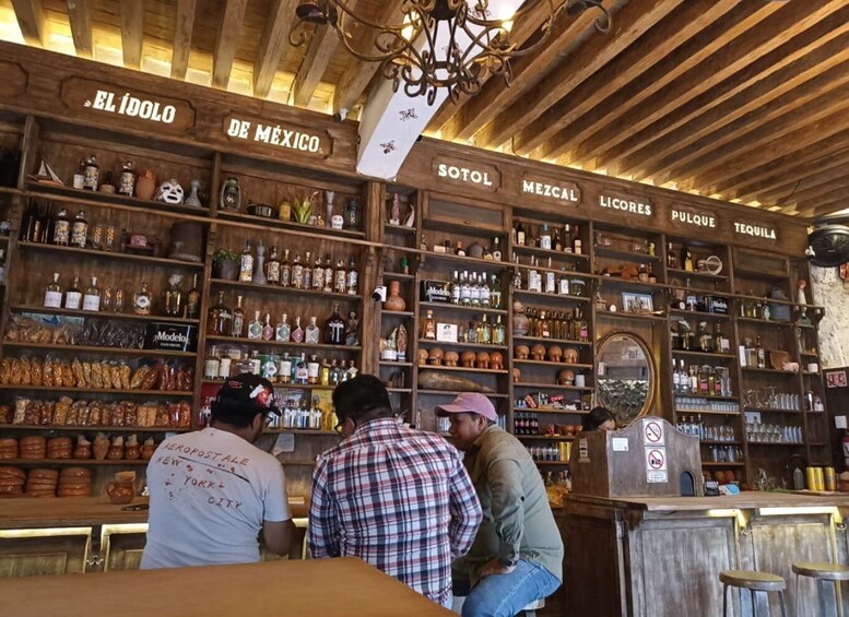 A bar with wooden shelves stocked with various bottles and a sign reading 'EL ÍDOLO DE MÉXICO.' 2