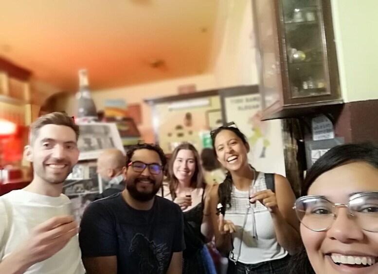 A group of people in a casual indoor setting with a counter and various items on display. 1