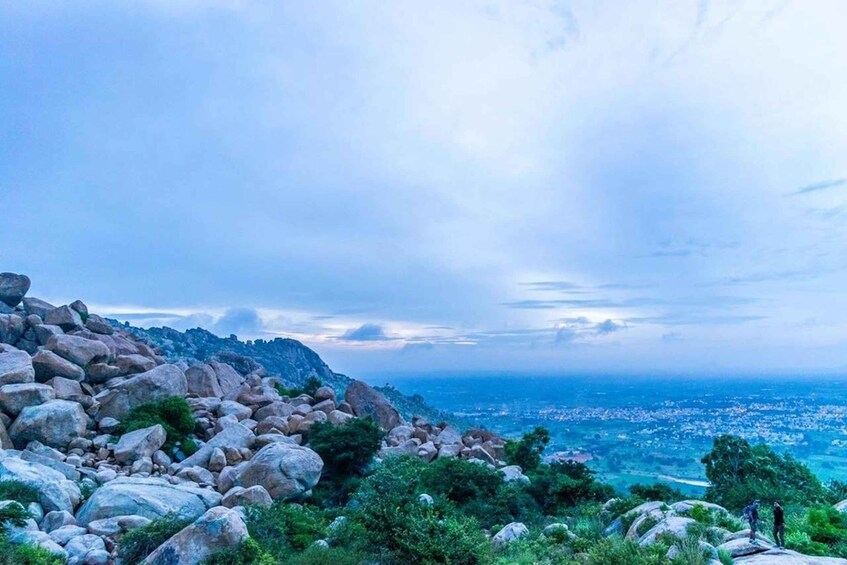 A rocky landscape with a city in the distance under a cloudy sky. 3
