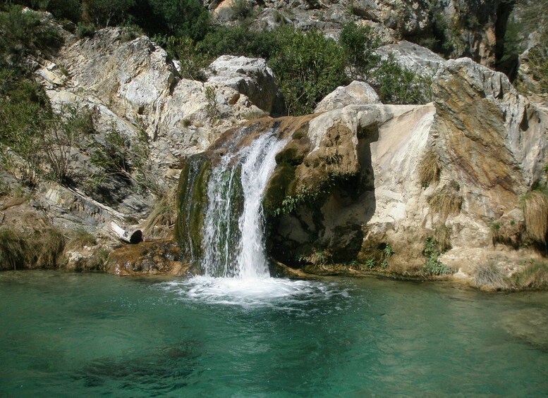 A waterfall cascading over rocks into a clear pool of water. 5