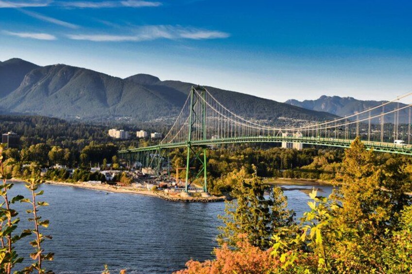 A suspension bridge over a river with mountains in the background. 2