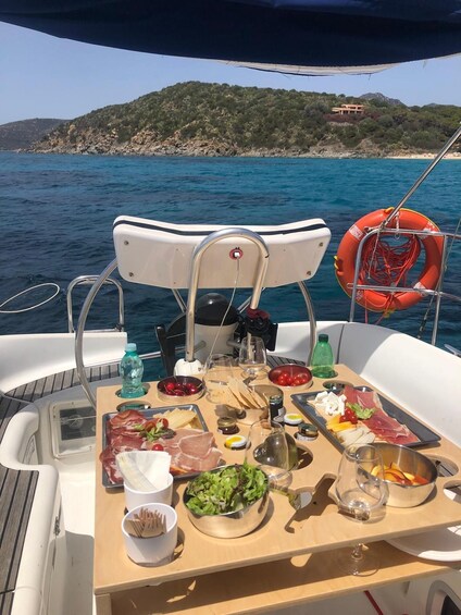A boat with a table set for a meal, surrounded by water and a hilly landscape. 3