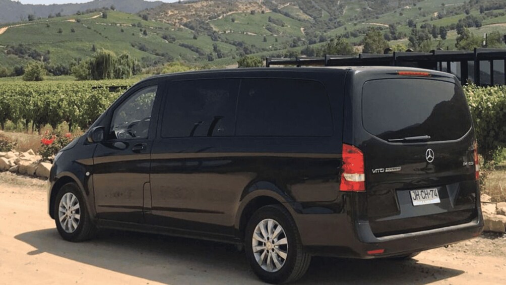 A black Mercedes van parked on a dirt road with a scenic hilly landscape in the background. 3