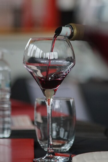 A wine bottle pouring red wine into a clear glass. 5