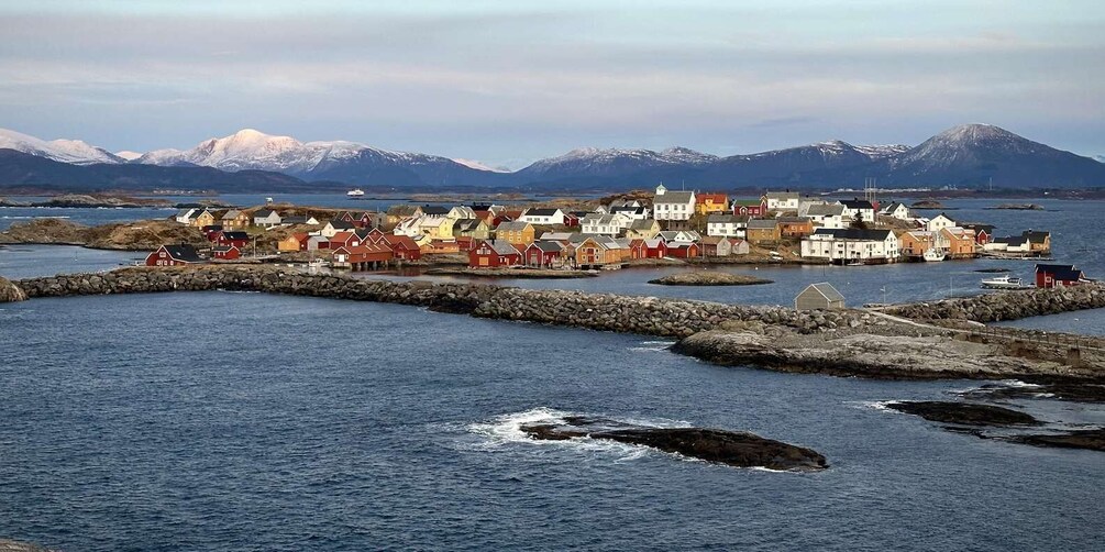 A coastal village with colorful houses, a stone breakwater, and snow-capped mountains in the background. 5
