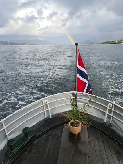 A boat with a flag, a rainbow, and a calm sea. 3