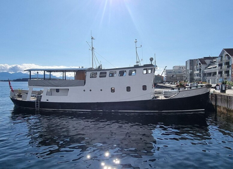 A large white and black boat docked at a pier with buildings in the background. 4