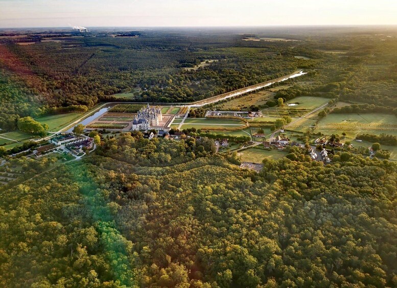 An aerial view of a castle surrounded by forested areas and fields. 5