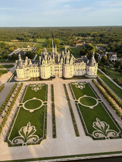 A grand château with symmetrical gardens and a forested backdrop. 4