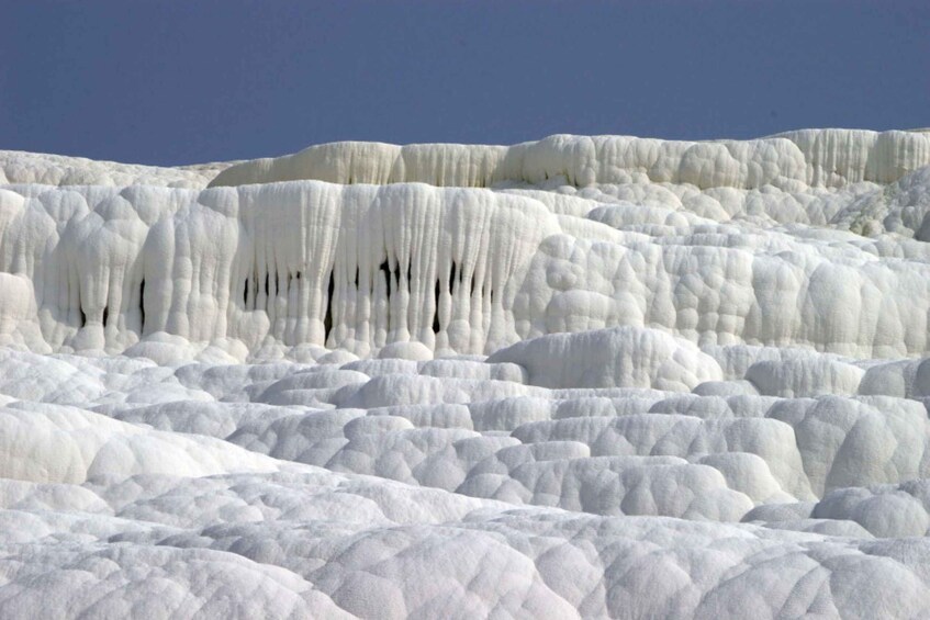 A landscape of white travertine terraces with cascading formations. 1