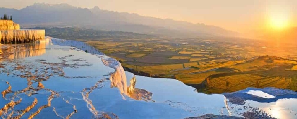 Terraced pools of water, a distant mountain range, and a sunset. 3