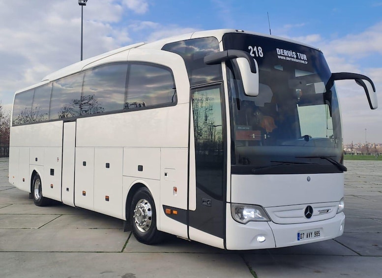 A white Mercedes-Benz Tour bus with the number 218 parked on a concrete surface. 4